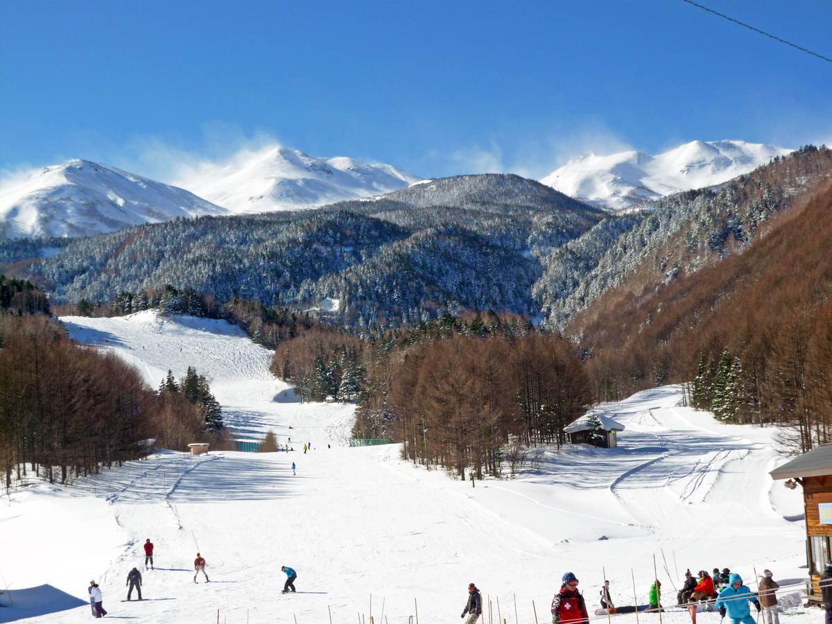 Skiers on a run at Mount Norikura with Mt Norikura's ridgeline behind, Matsumoto, Nagano